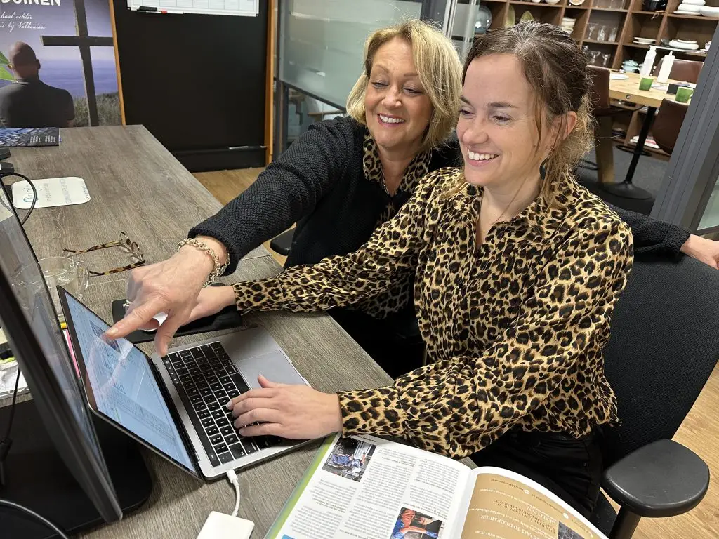 Officemanager Anja en vormgeefster Andrea werken aan de nieuwste editie van de Arne Courant.